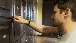 Close up of a male's profile as he raises his hand to the cabinent on the wall