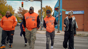 Freedom Jones crossing the street with men waring orange safe streets jackets