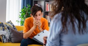Teen male looking off to the side with doctor facing him