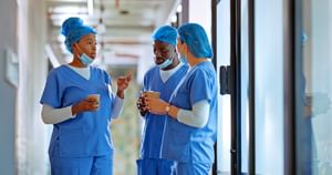 3 health care professionals in scrubs holding coffee while chatting