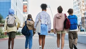 Backs of children walking away with various backpacks