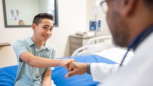 A doctor doing a fist bump with his patient smiling at him.