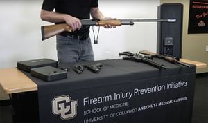 Close-up of white male holding a rifle gun at a booth for the firearm injury prevention initative at the University of Colorado