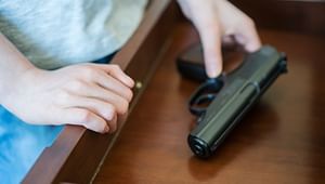 Youthful hands picking up a handgun in a drawer