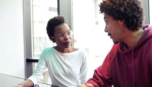Two young people talking infront of a window