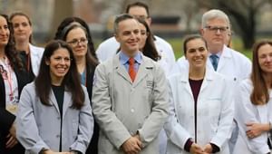 Health care professionals in their white coats standing outside smiling