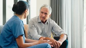 Woman medical professional speaking as she sits across from a white male listening attentively