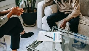 Close up of two individuals sitting across from each other with a clip board on table